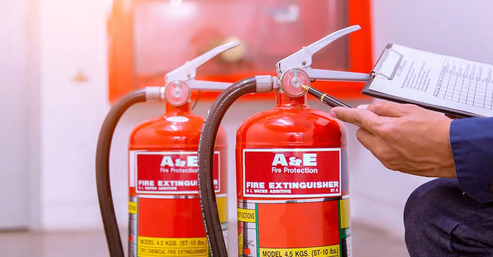 Engineer inspecting fire extinguisher pressure gauges, serviced by INET Fire & Security